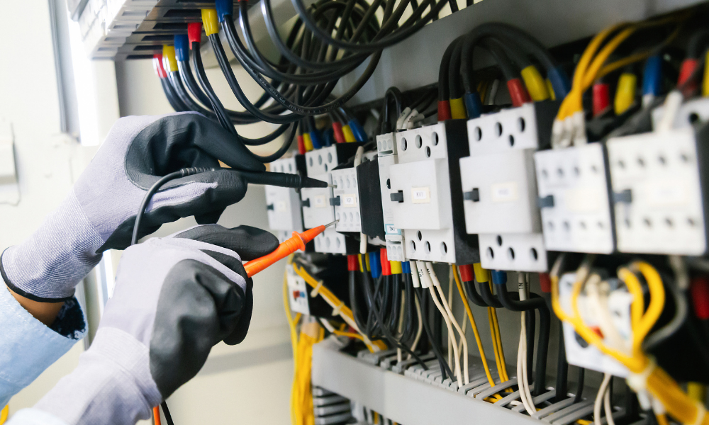An engineer performing electrical testing on a control panel